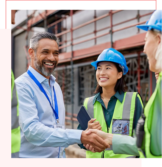 Construction professionals shaking hands at a building site.