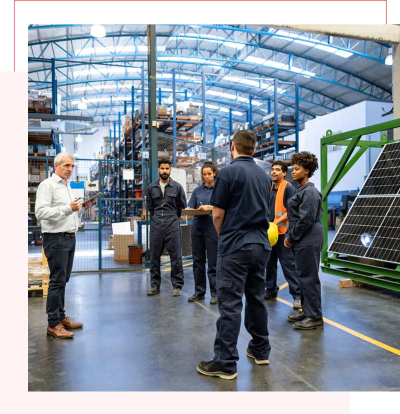 Technician explaining solar panel setup to a group in a factory.