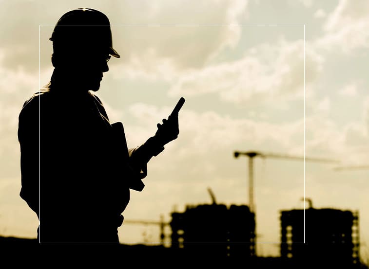 A man in hard hat looking at his cell phone.