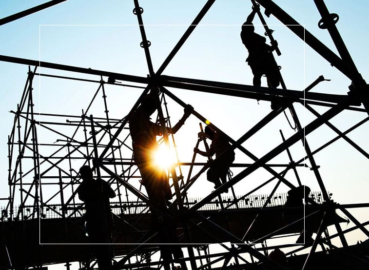 A group of men working on scaffolding in the sun.